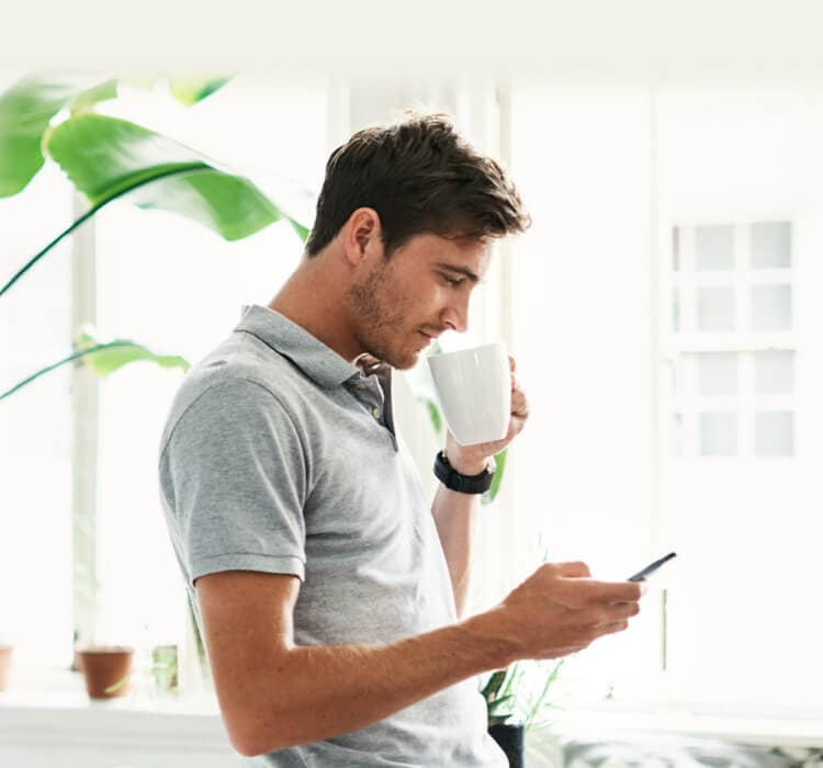 Mężczyzna pijący kawę i trzymający w dłoni telefon komórkowy
