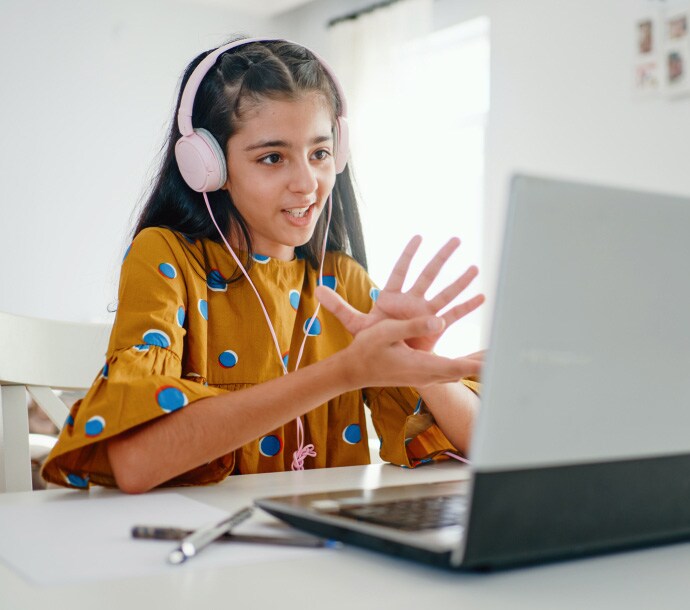 Dziewczyna przy biurku korzystająca z laptopa, na którym uruchamia się program Norton Family.