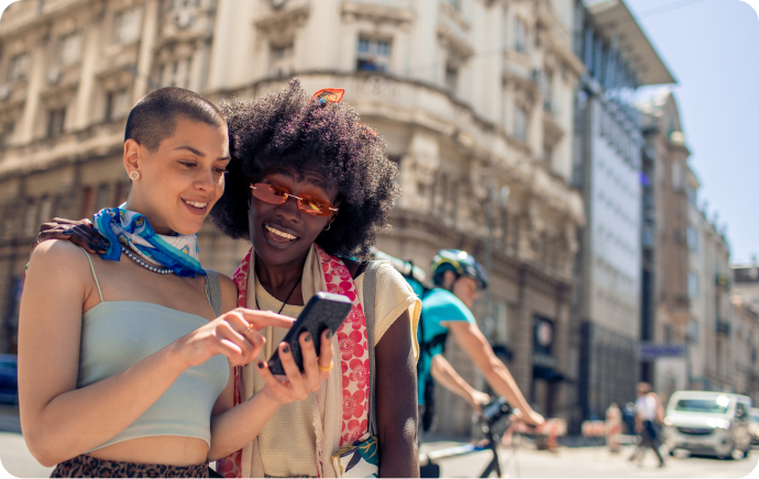 Dwie kobiety uśmiechające się i spoglądające na telefon